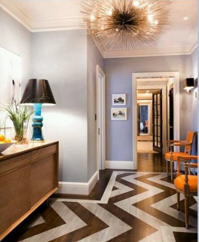 Choosing a soft wall color and using a pair of subtle warm orange chairs with a teal blue lamp add a fresh pop to this hallway